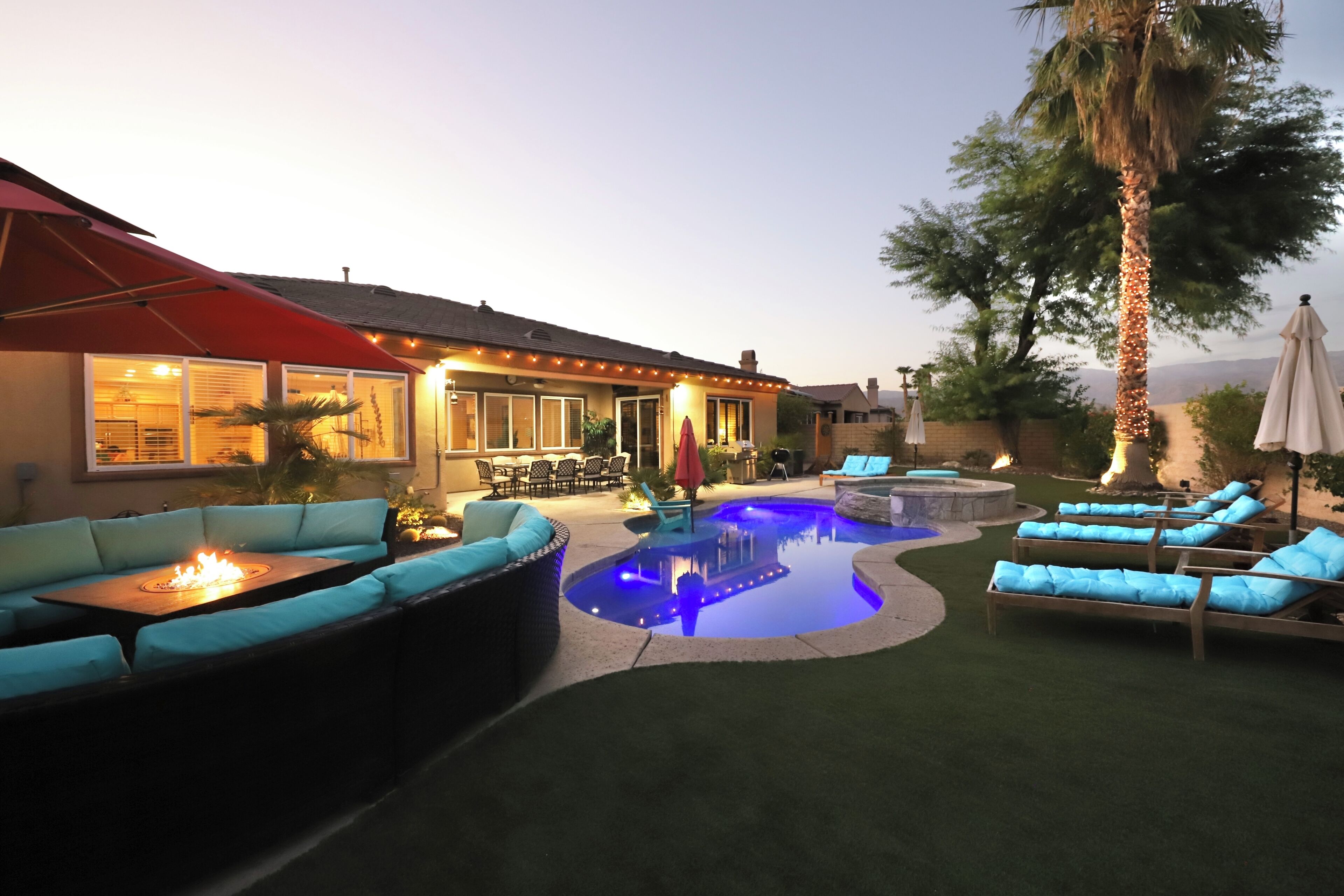 A backyard with a swimming pool, outdoor seating, and a patio area.