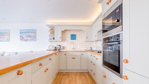 Een moderne keuken met witte kasten, houten aanrecht en een ingebouwde oven.