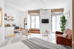 A modern, compact living space with a kitchenette, a dining area, a sofa, and a TV. - JOIVY Sophisticated studio near Convento do Carmo (Lisboa)