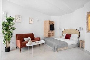 A modern bedroom with a bed, a wooden wardrobe, a red sofa, a white coffee table, and a potted plant. - JOIVY Sophisticated studio near Convento do Carmo (Lisboa)