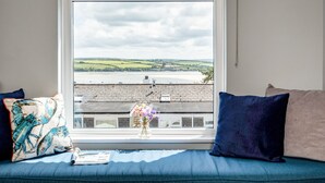 A room with a view of a coastal landscape through a window.