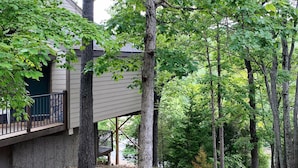 Ett bostadsområde med ett hus, ett träd med en tjock stam och en träveranda.
