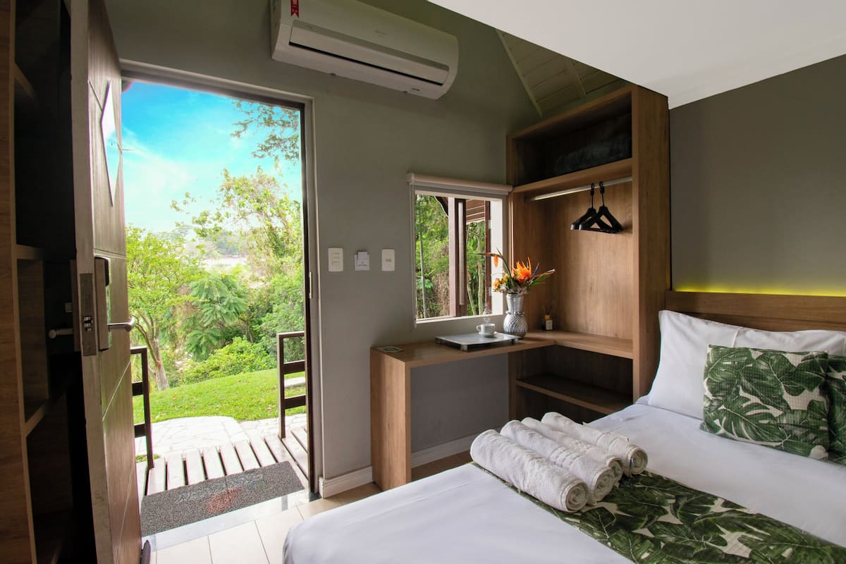 Une chambre à coucher avec un lit, un bureau et une fenêtre donnant sur un paysage verdoyant.