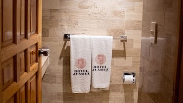 Un bagno d'hotel con una parete in pietra, due asciugamani su un porta-asciugamani e una porta in legno.