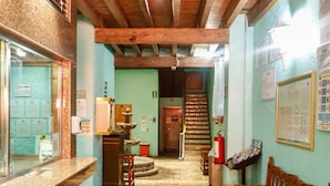 A hallway with a wooden ceiling, a reception desk, a bench, and a fire extinguisher. - Hotel Juarez (Mexico City)