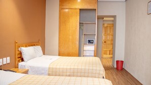 A hotel room with two beds, a wooden headboard, a wardrobe, a small desk, and a red trash bin. - Hotel Juarez (Mexico City)
