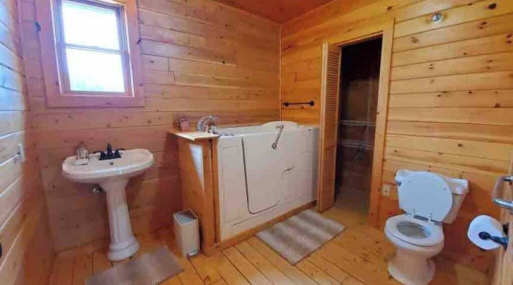 A wooden cabin bathroom with a sink, toilet, and shower.