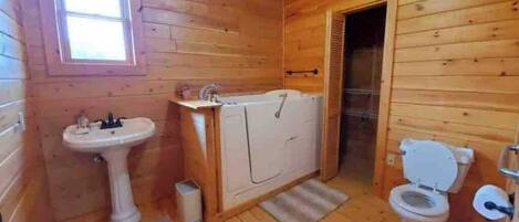 A wooden cabin bathroom with a sink, toilet, and shower.