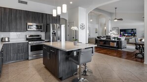 A modern kitchen with dark cabinetry, stainless steel appliances, and a central island with bar stools.