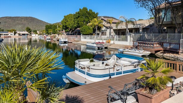 A marina with boats docked, a wooden deck, and a mountain in the background.