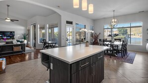 A spacious kitchen with a large island, dark cabinetry, and pendant lighting.