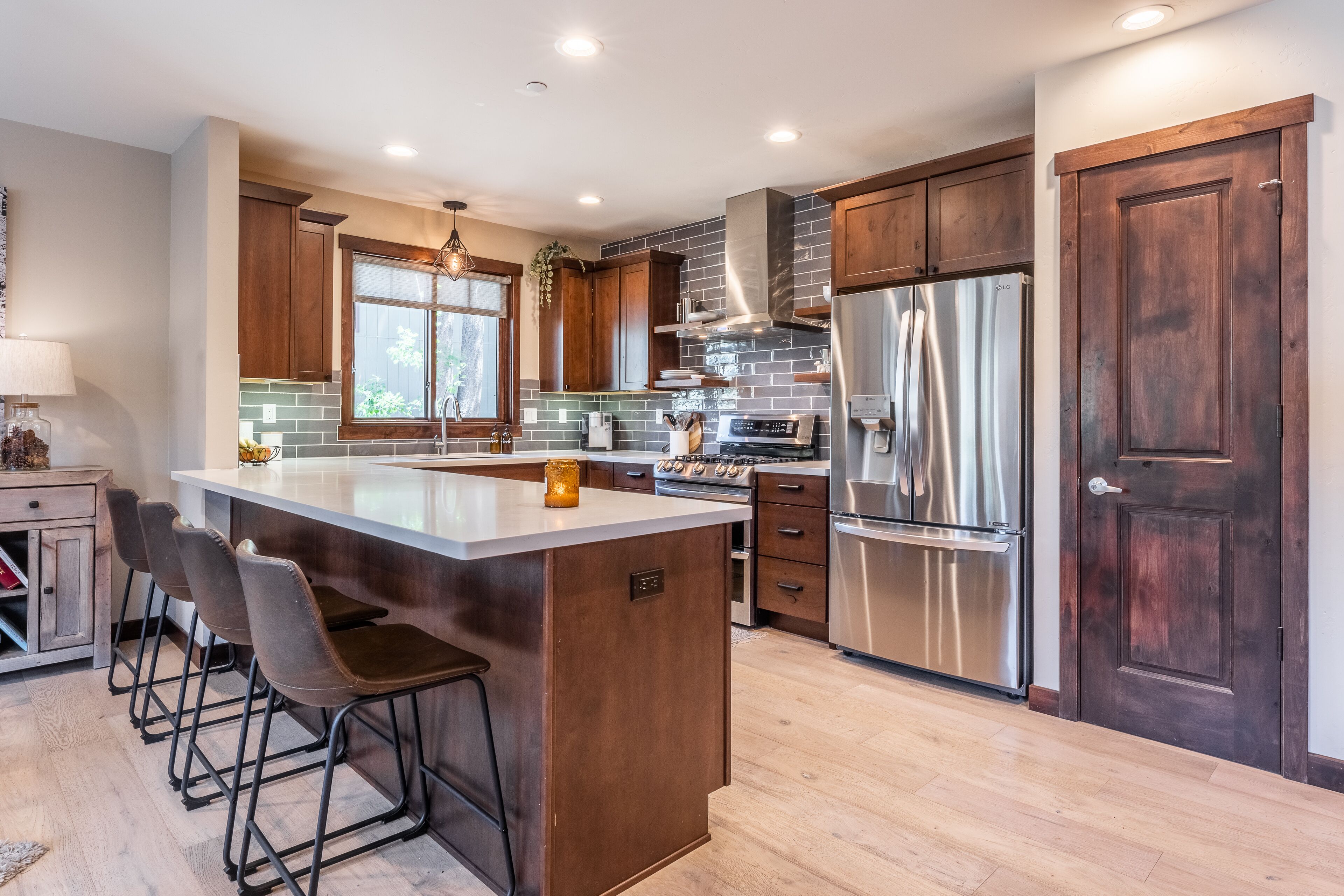 A modern kitchen with a large island, stainless steel appliances, and wooden cabinetry.
