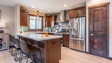 A modern kitchen with a large island, stainless steel appliances, and wooden cabinetry.