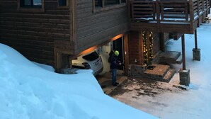 Un chalet en bois, dont le toit est recouvert de neige, et qui possède un balcon illuminé.