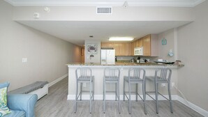 A modern kitchen with a central island, bar stools, and wooden cabinets. - Amazing Views from this waterfront condo. (Pensacola)