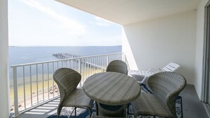 A balcony with wicker furniture, a view of the sea, and a pier in the distance. - Amazing Views from this waterfront condo. (Pensacola)
