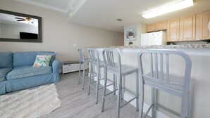 A compact living space with a kitchenette, a sofa, and a bar area with stools. - Amazing Views from this waterfront condo. (Pensacola)