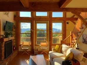 Relax in this spacious room with a comfortable seating area, fireplace, and large windows offering views of the surrounding landscape.