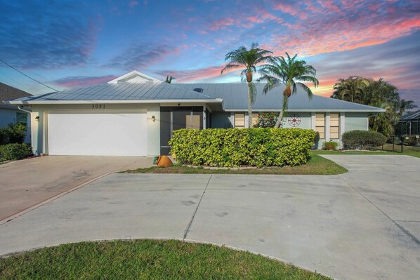 A single-story house with a garage, a well-maintained lawn, and a palm tree.