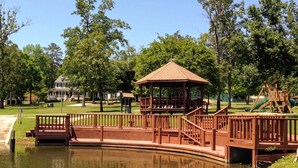 A park with a wooden bridge over a pond, a gazebo, and playground equipment. - Lake living in a relaxed family and pet-friendly home (Chapin)