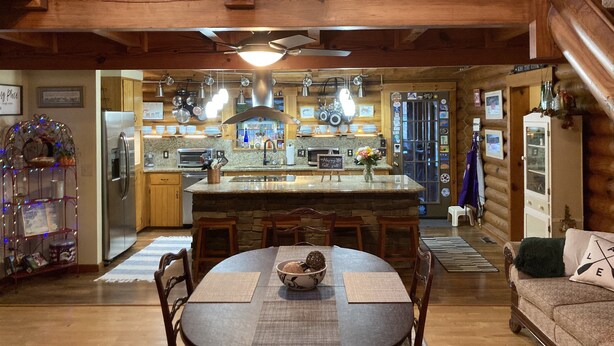 A cozy cabin interior with a wooden dining area, kitchen, and a living space with a couch. - Lake living in a relaxed family and pet-friendly home (Chapin)