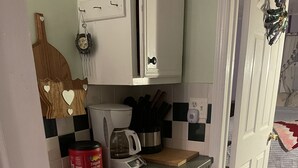 Uma cozinha compacta com cafeteira, lixeira e micro-ondas.