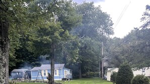 Um bairro residencial com uma casa azul, baloiço e relvado.