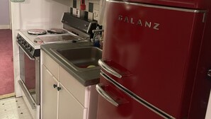 Uma cozinha compacta com uma geladeira Galanz vermelha, um fogão branco e uma pia.