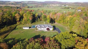 Une grande maison dotée d’une vaste pelouse et offrant une vue sur la campagne environnante.