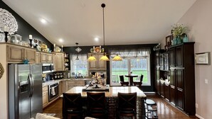 Une cuisine spacieuse dotée d’un îlot central, de meubles en bois et d’une grande fenêtre offrant une vue sur l’extérieur.
