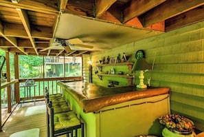 A rustic kitchen with wooden beams, a green wall, and a bar area with stools.