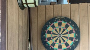 A dartboard mounted on a wooden wall with a single dart in the center. - Escape To The Hacienda (Ben Lomond)