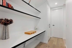 Um interior moderno com parede branca, estantes pretas, uma caixa de madeira e um vaso estampado.