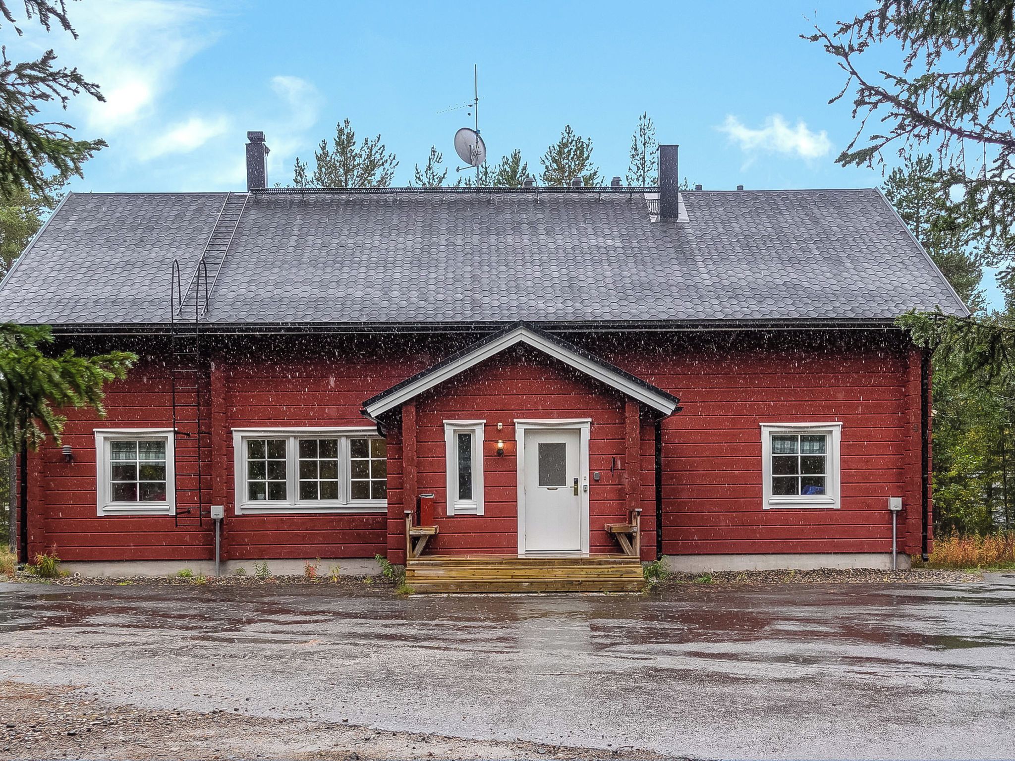 A red wooden house with a white door, two windows on the front, and a small porch.