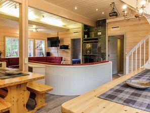 A cozy interior with a wooden dining area, a kitchen with a stone backsplash, and a staircase leading to another level.