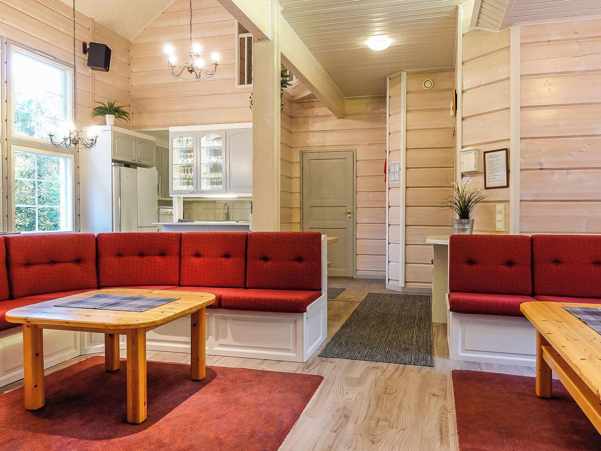 A cozy interior with a red sofa set, wooden coffee table, and a kitchen area with white cabinets.