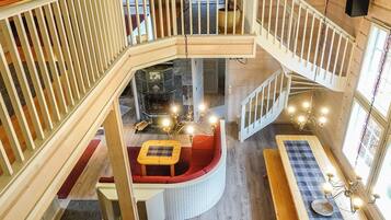 A multi-level interior with a central seating area, wooden railings, and a staircase.