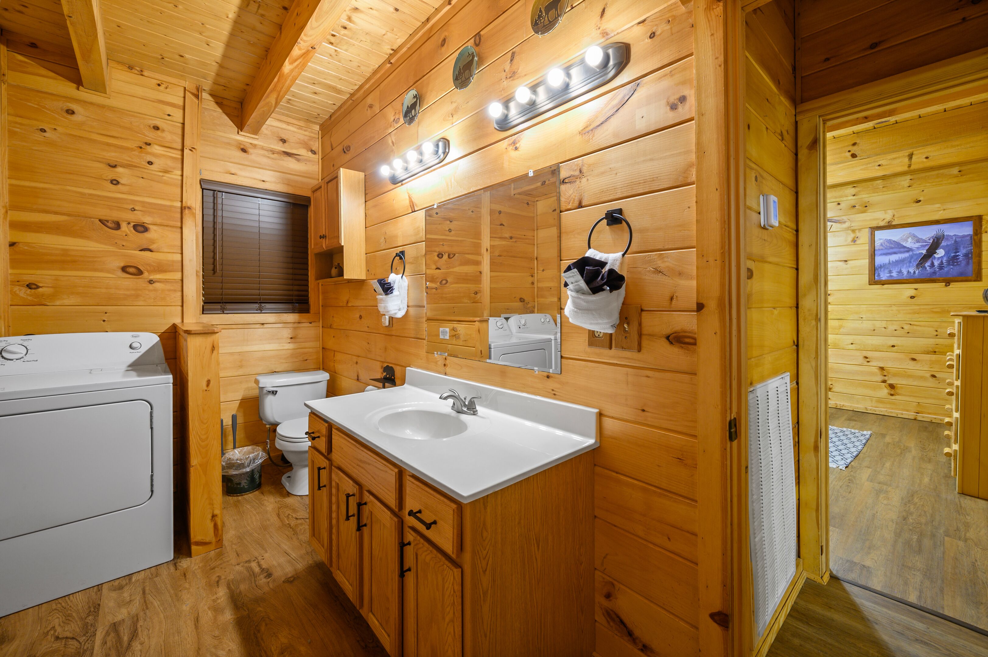 A wooden cabin bathroom with a washing machine, sink, and toilet.