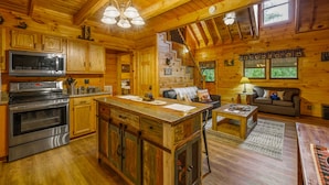 A wooden cabin interior with a kitchen, dining area, and living room. - Springtime Specials! Secluded Log Cabin-NEW Hot Tub-Wrap Around Porch (Sevierville)