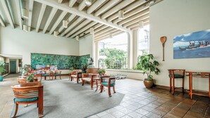 A spacious lobby with wooden furniture, a large green mural, and a view of the outdoors.