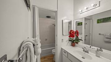A modern bathroom with a white sink, mirror, and shower.