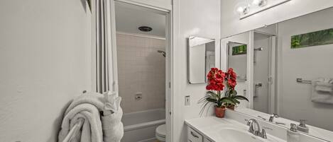 A modern bathroom with a white sink, mirror, and shower.