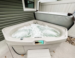 A hot tub with a control panel, set against a house with siding and a window. - 2 Br home with Hot-Tub! Quiet, dead end street (Millersburg)