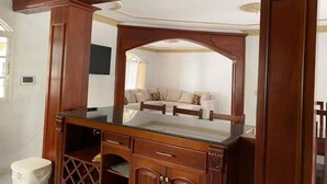 Une pièce comprenant une coiffeuse en bois, un miroir, un canapé et un téléviseur.