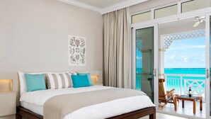 Une chambre avec un lit, une table de chevet, une chaise et un balcon donnant sur l’océan.