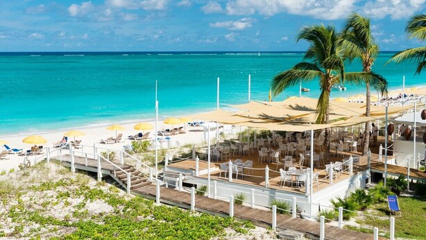 Un complexe hôtelier situé en bord de mer, doté d’une piscine, de chaises longues et de parasols.