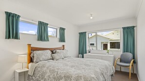 Un dormitorio con una cama grande, una mesita de noche, una silla y un aparador.