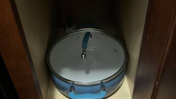 A compact storage space with a blue container and a lid, a shelf above, and a door with a lock.