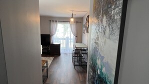 A hallway with a dining area, a painting on the wall, and a ceiling fan.