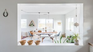 A bright, modern dining area with a wooden table, chairs, and hanging pendant lights.